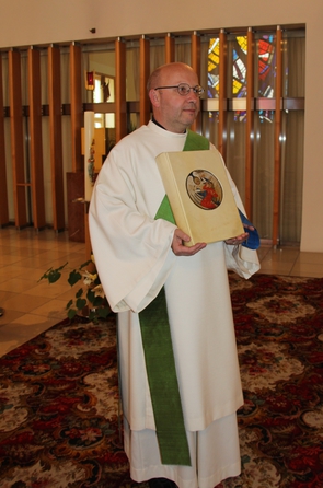 Diakon mit weißer Dalmatik und schräg gekreuzter Stola trägt das Evangeliar. © Isabella Unfried